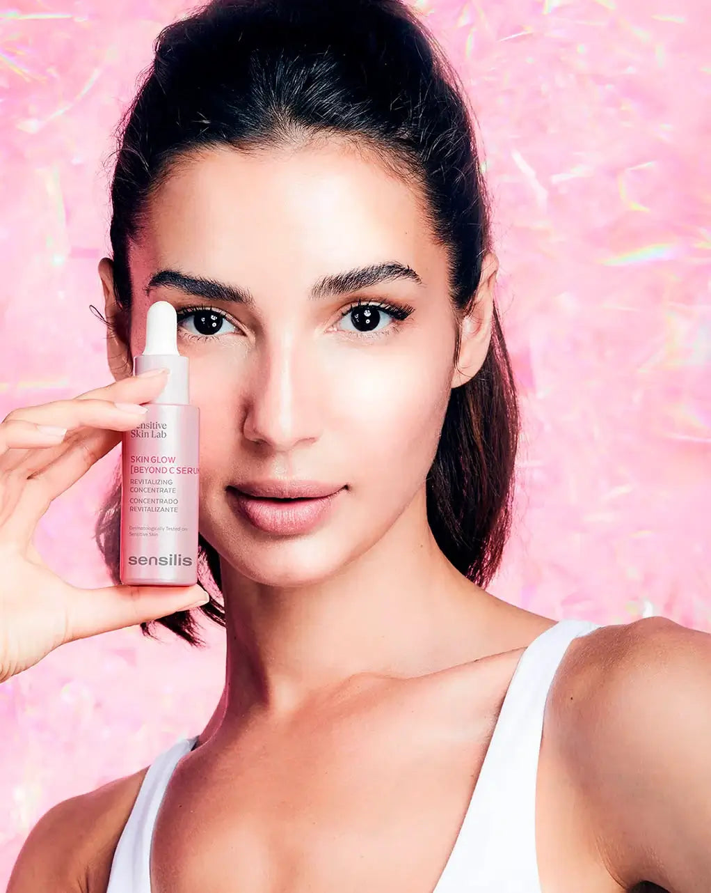 Sensilis Skin Glow Beyond C Serum 30ml in gebruik door model met stralende huid en roze achtergrond