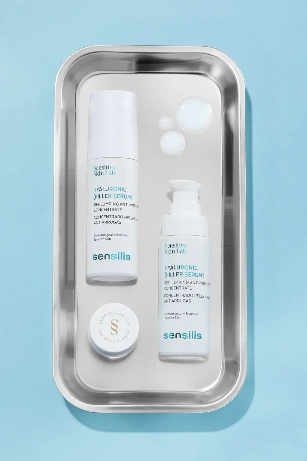 Sensilis Hyaluronic Filler Serum 30ml met serumflacon en oogcrème op een metalen schaal voor optimale hydratatie en volume.