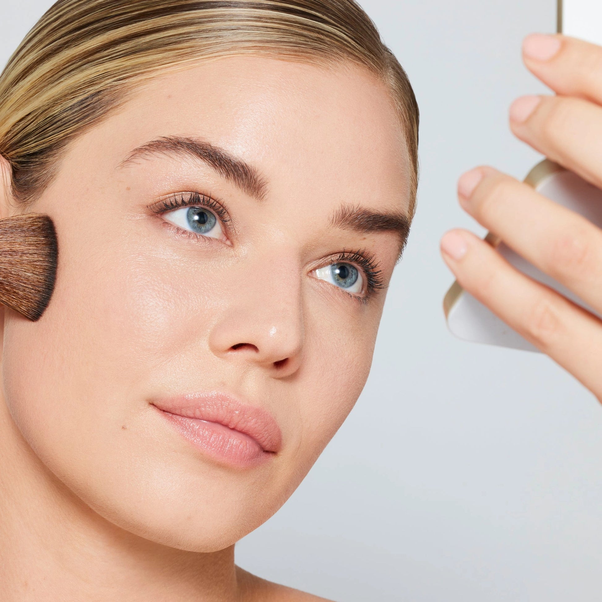 Jane Iredale PureMatte Finish Powder Refill 9,9g aangebracht met een kwast, vrouw die zich opmaakt, natuurlijk matte huid.