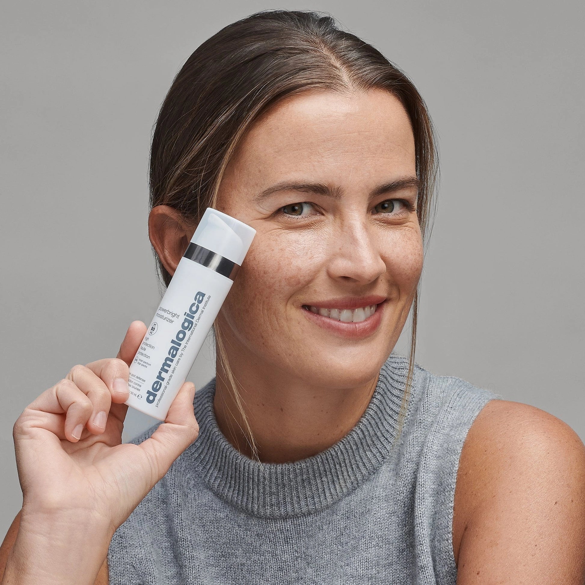 Dermalogica PowerBright Moisturizer SPF50 50ml in de hand van een vrouw met stralende huid, tegen pigmentvlekken.